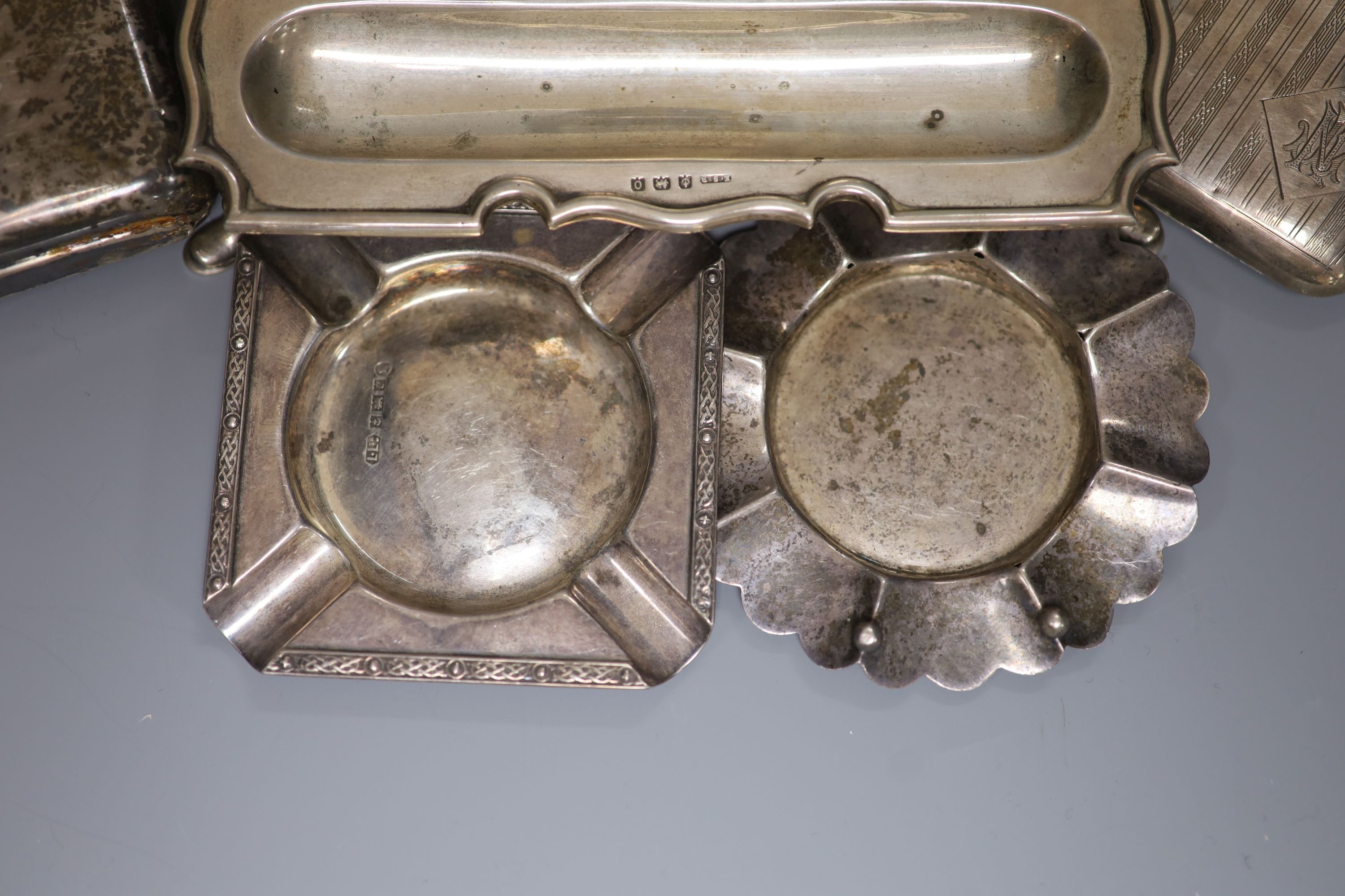 A silver shaped rectangular inkstand, fitted a silver-mounted cut glass bottle, a silver hip flask, engine-turned cigarette case and two ashtrays 13.5oz approximately